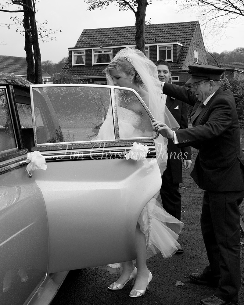 A rainy day wedding in Leeds - The bride getting into a vintage wedding car after the church ceremony