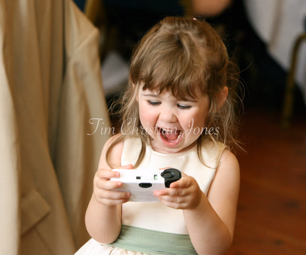Bridesmaid laughing doing a selfie with a single use camera