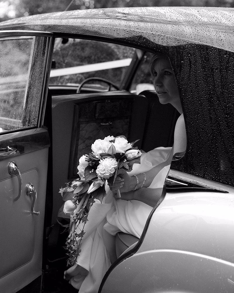 Candid wedding moment bride inside wedding car in the rain