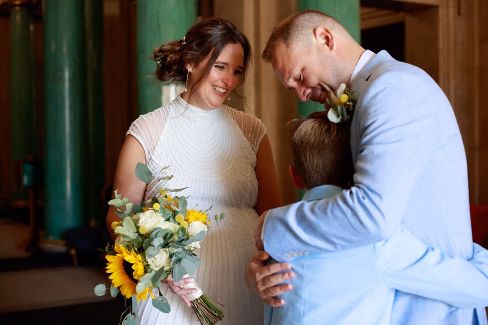 Groom hugging his young son outside Leeds Civic Hall as the moment slows before portraits begin.