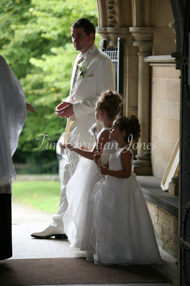 Groom looking pensive with his 2 bridesmaids talking to the Father