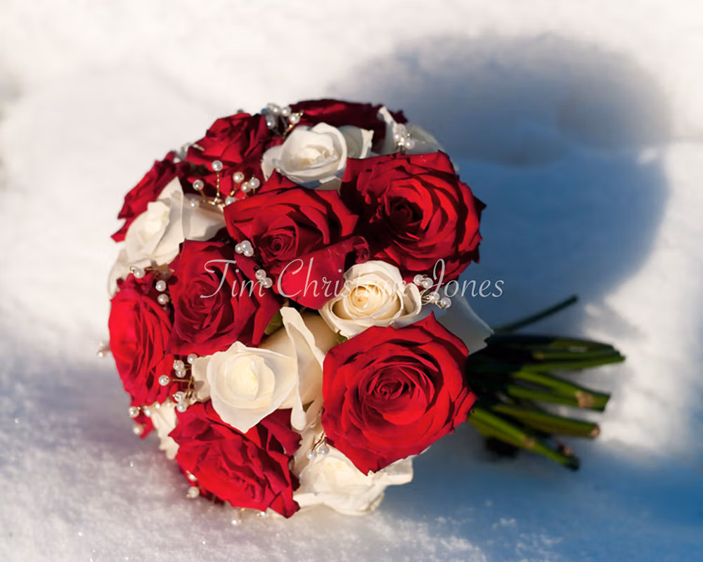 The bride's bouquet in white and red roses at a Leeds Winter Wedding - placed in the white snow