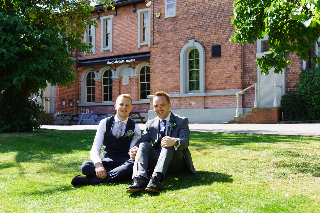Christian and Jason sat on the grass - a natural couple portrait outside The Faversham Leeds