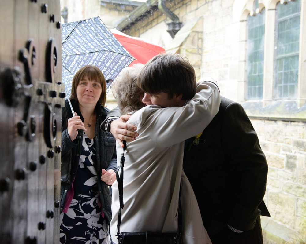 UK Wedding Photography by Tim Christian Jones - Dan the groom greets guests inside the entrance of the church.