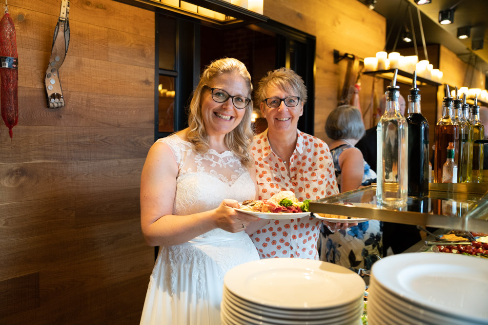 Clare & Tracey's DoubleTree Hilton wedding in Leeds - candid moment - the couple with plates or food smiling - at their Fazenda wedding breakfast in Leeds by Tim Christian Jones.