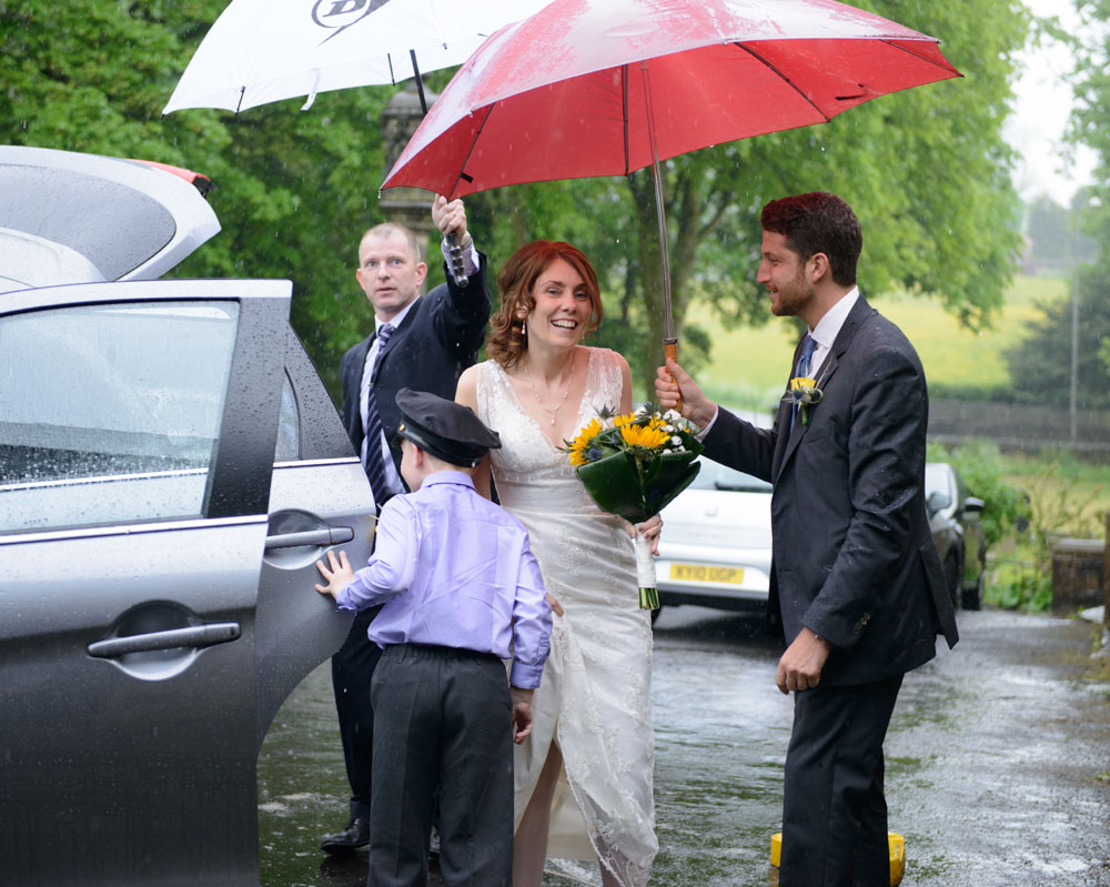 A rainy day wedding in Leeds - The bride getting into a vintage wedding car after the church ceremony