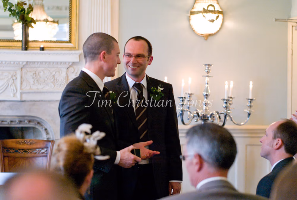 Groom and best man stand side by side, the ring box clasped with focus and care.