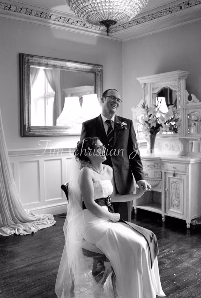 A relaxed portrait showing Julie seated and Pat standing — both beaming with joy.