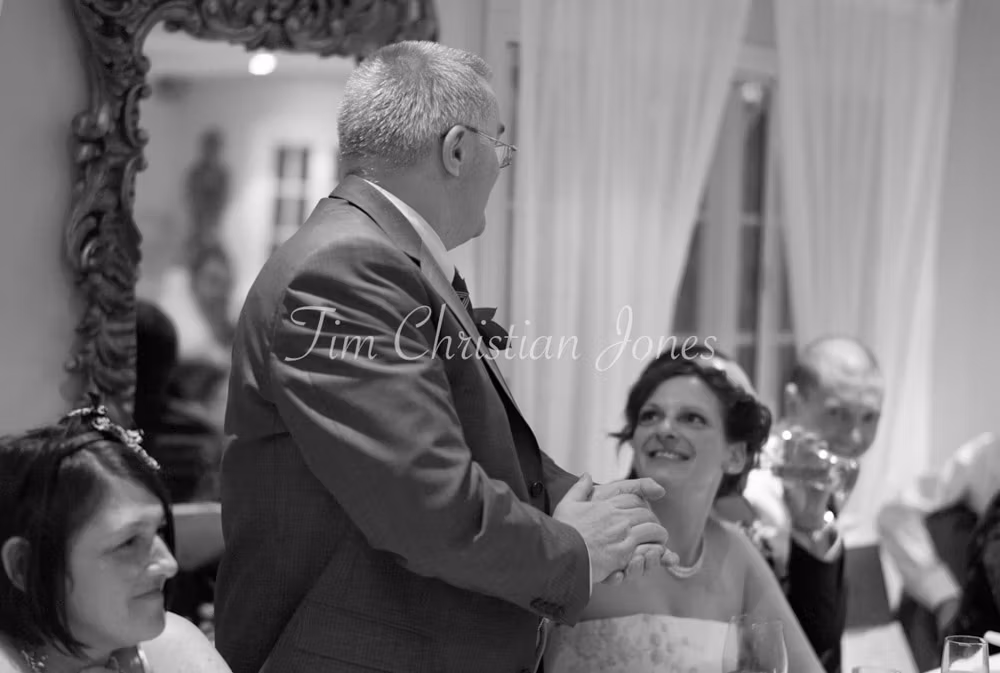 The father of the bride stands to deliver a heartfelt speech, emotion in his eyes.