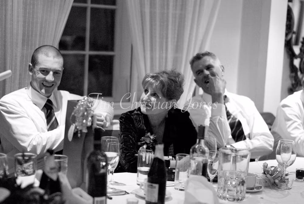 Guests at the top table listen in as the best man prepares to speak, all eyes on him.