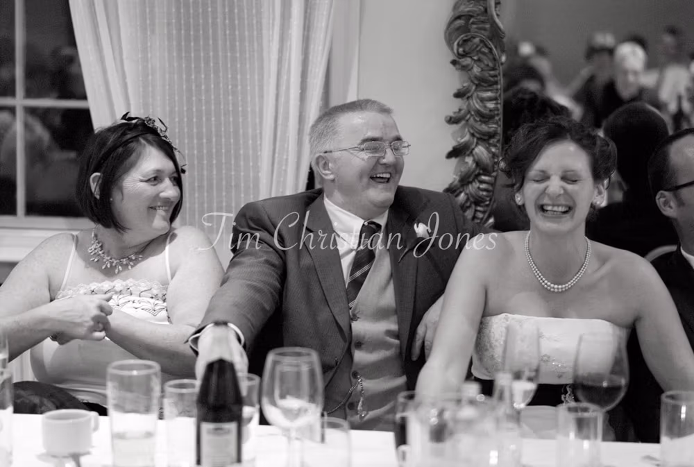 Julie and her parents share a moment of laughter, visibly enjoying the speeches.