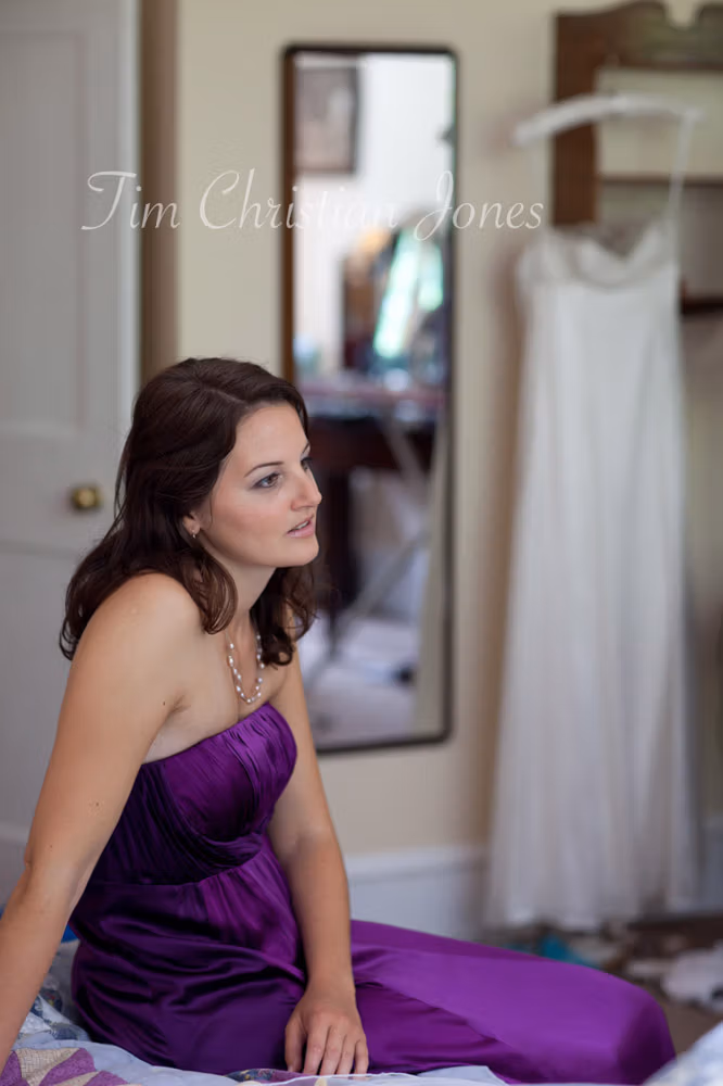 Bridesmaid on the bed with the bride’s dress behind at the Temple of Apollo, Stourton
