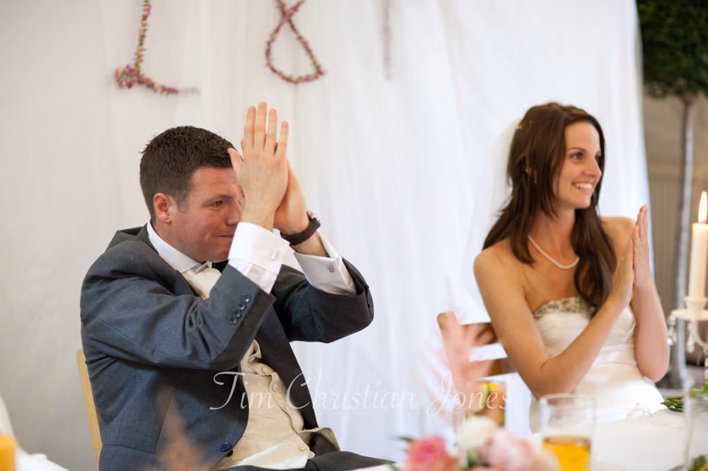 Bride and groom applauding during the best man’s speech