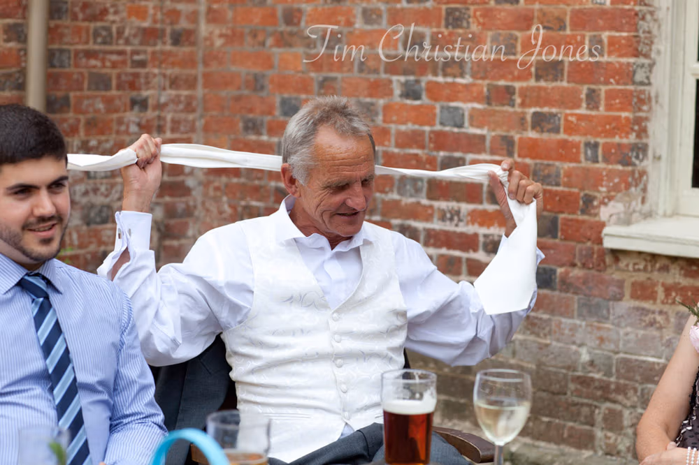 Father of the bride taking off his cravat to unwind after speeches