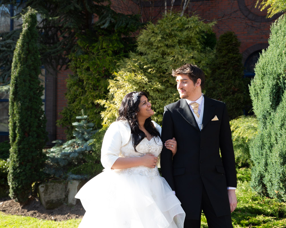 Zehra smiles radiantly beside Richard in the March sunshine as they pause for a wedding portrait at Crowne Plaza Leeds
