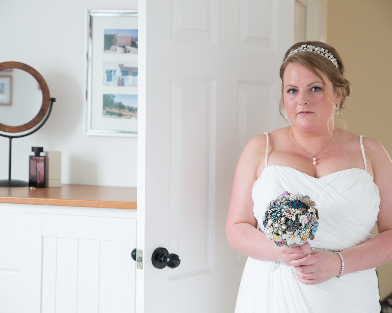 Bride holding an original costume jewellery and faux flower bouquet, quietly reflecting before her Scarborough Spa wedding.