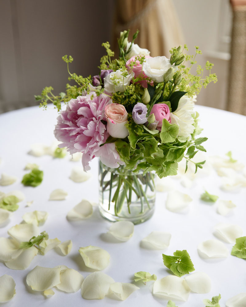 Flowers in a glass jar on the ceremony table surrounded by petals.