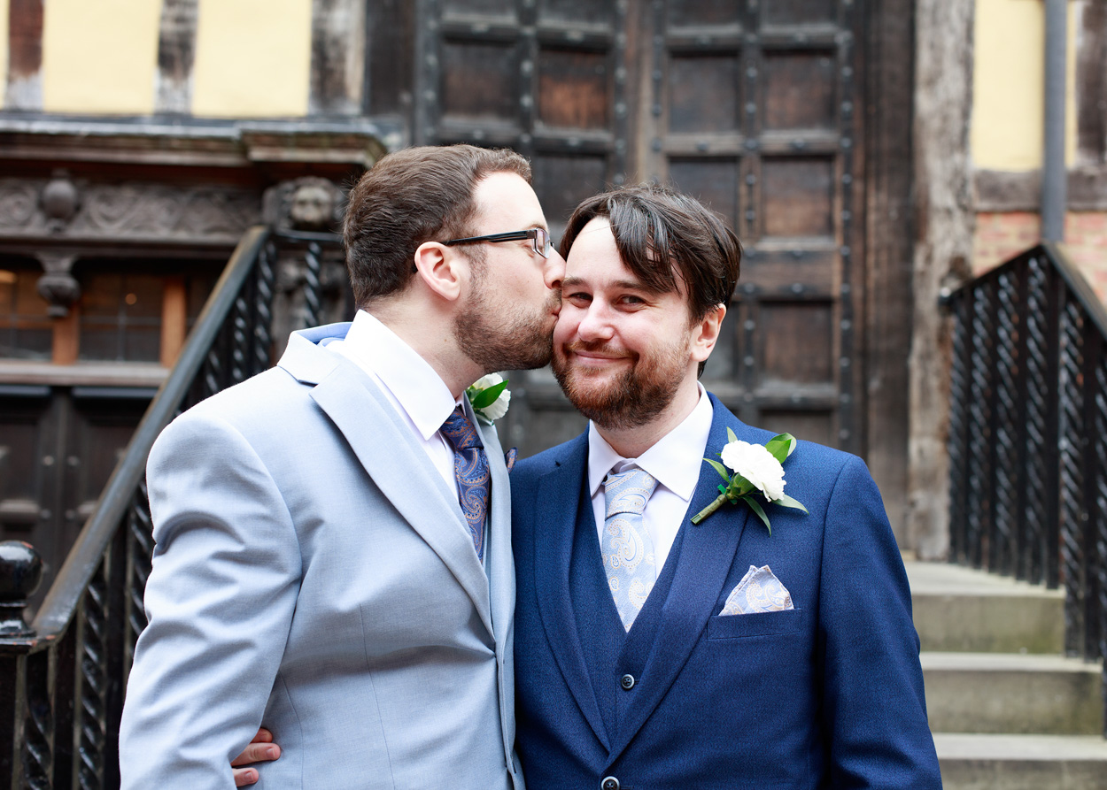 Close portrait of Chris and David sharing a kiss on the cheek before their wedding ceremony.