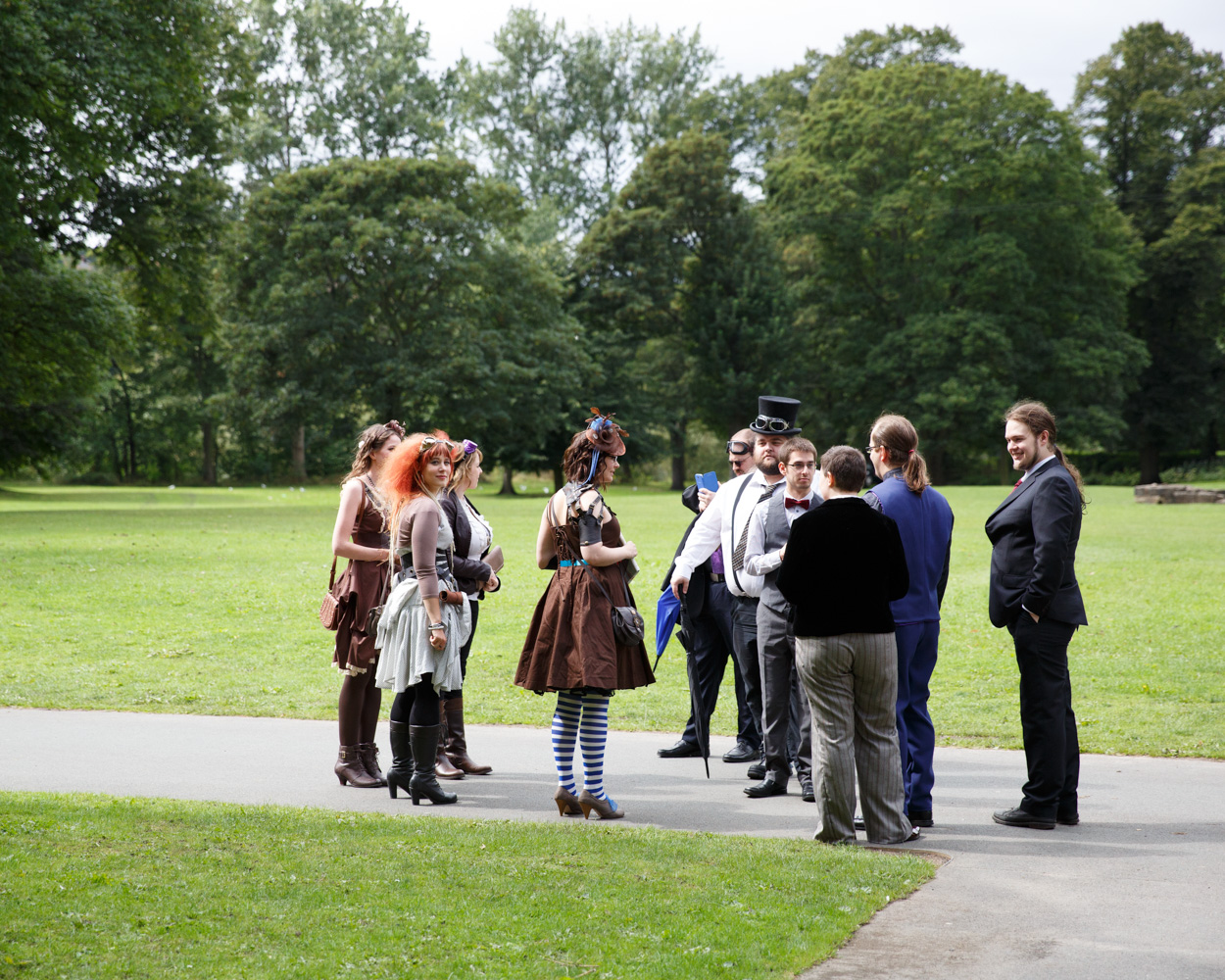 Friends arrive along the path outside the Abbey gates, framed by green grass and trees at Kirkstall Abbey