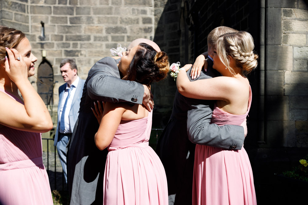 Bridesmaids arriving at the church are greeted with hugs from smiling boyfriends.