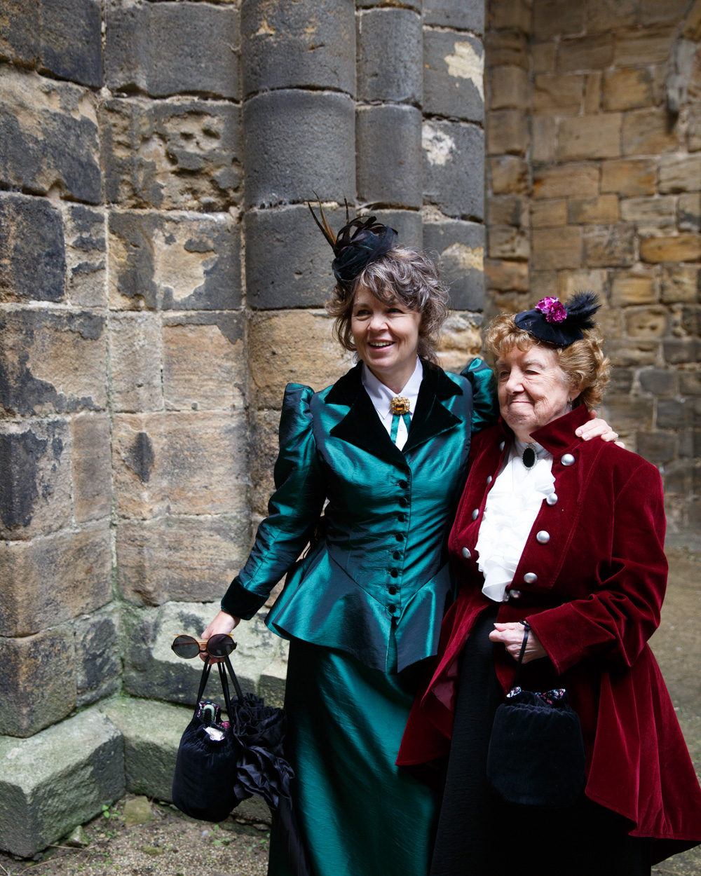 Mother and grandmother pose proudly beside the weathered stone walls of Kirkstall Abbey