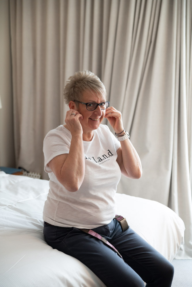 Tracey putting on her earrings sat on the bed