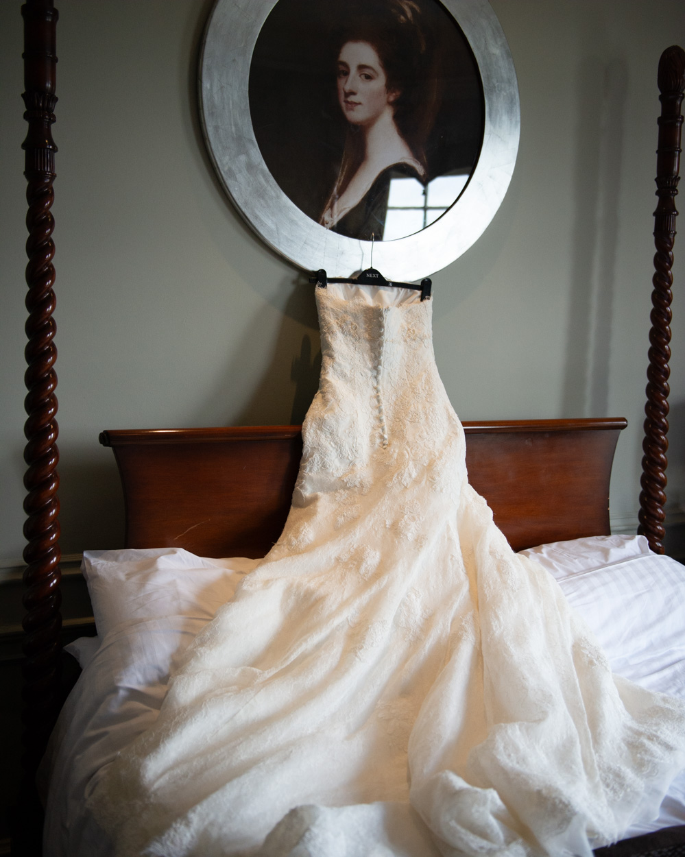 Wedding dress hanging from a picture frame above the bed