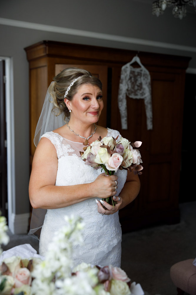 Bride smiling while holding her bouquet, posing with playful energy