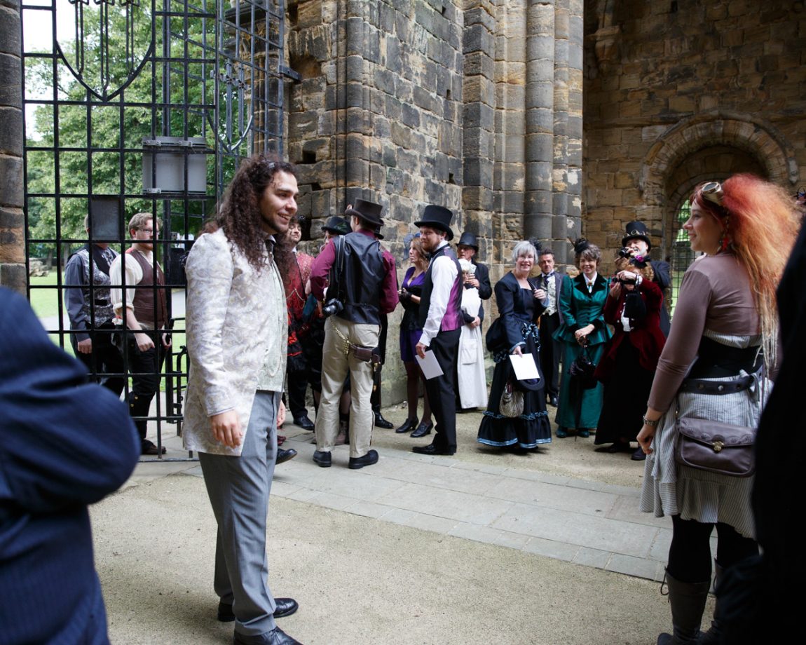 006 the groom in grey and light green greets guests inside abbey church kirkstall abbey wedding linsey and chris