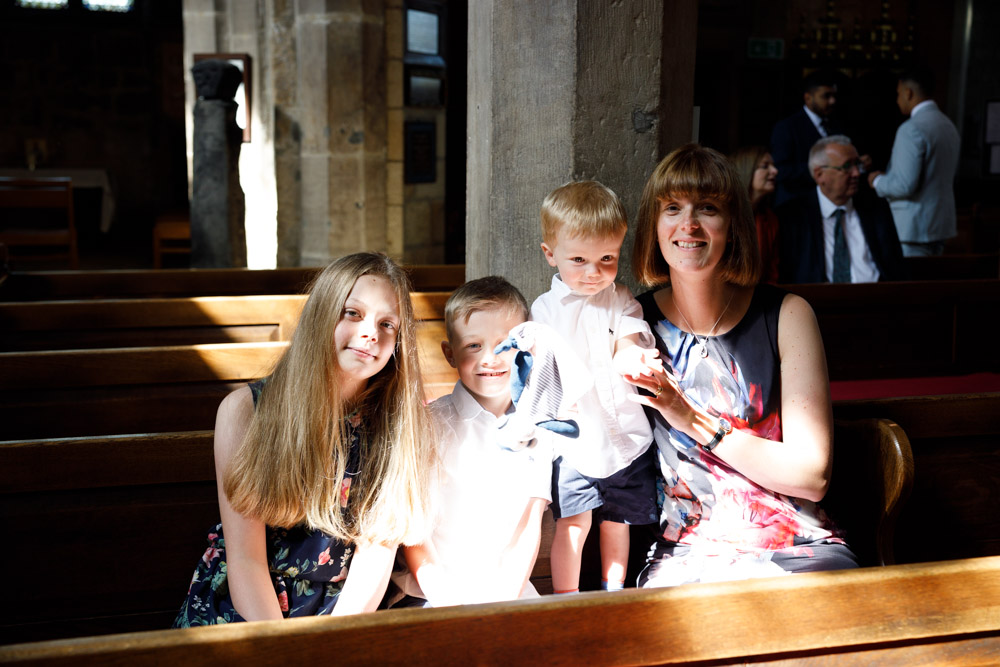 Young family sitting near a window inside the church, caught in soft light and shadow.