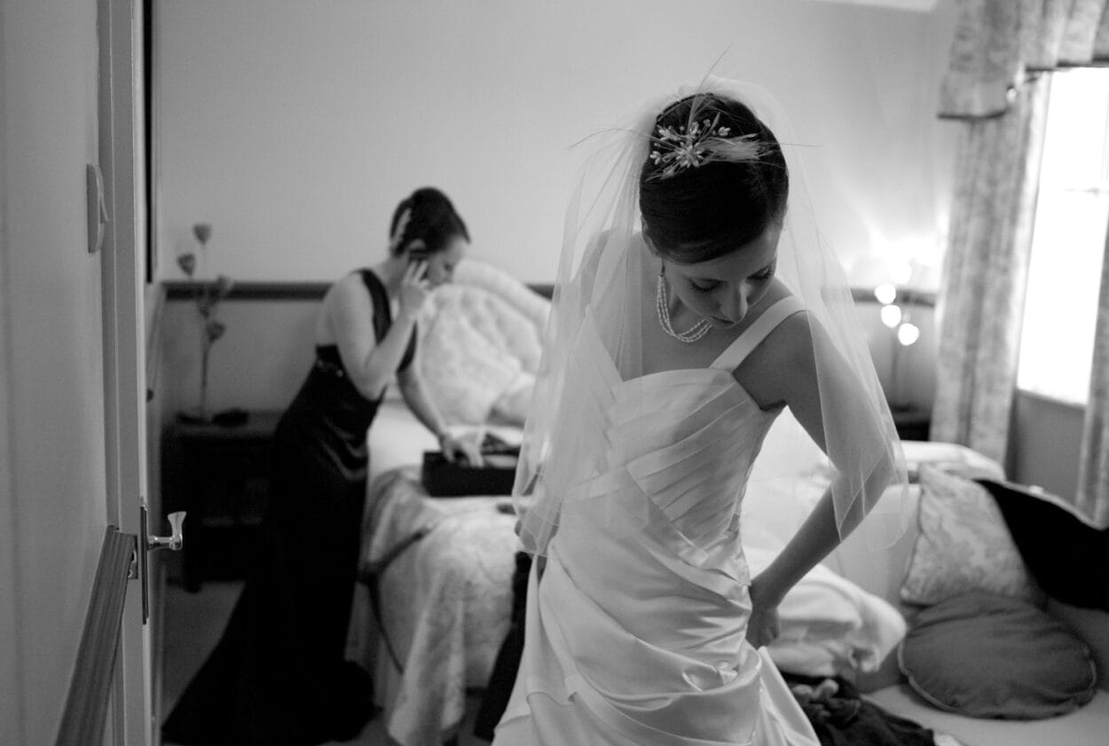 Emelie looks over her dress while her sister talks on the phone in the background.