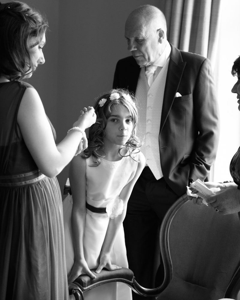 Young bridesmaid leans on a chair arm and notices the camera.