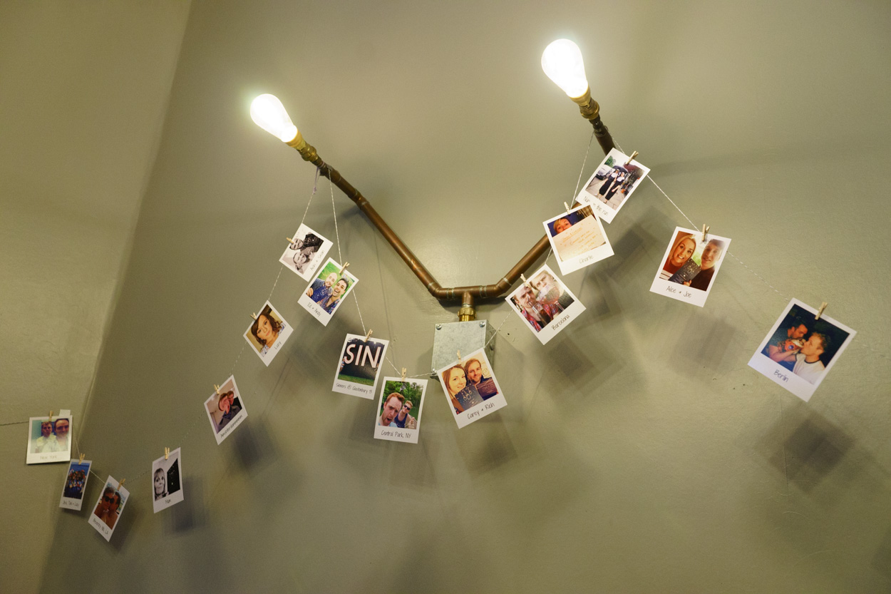 Polaroid photographs pegged above wall lights at a wedding venue
