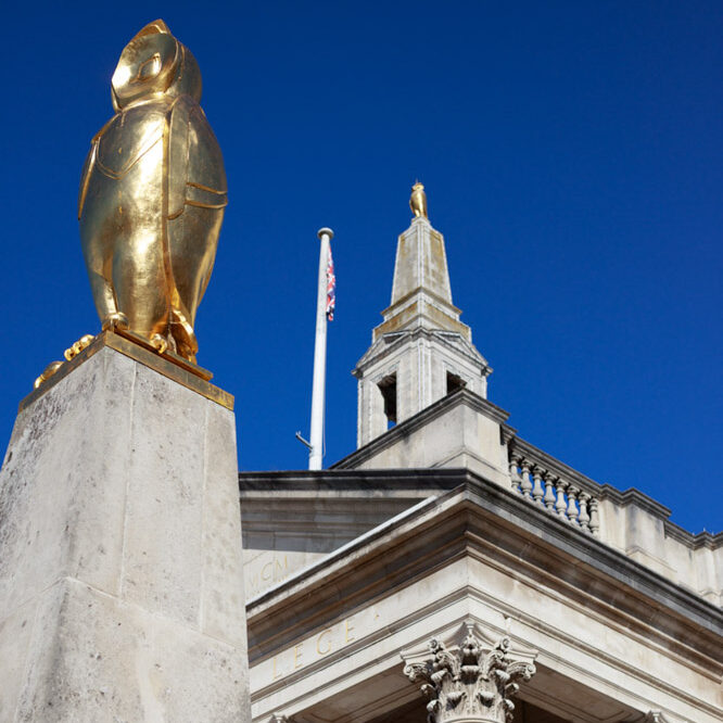 Golden owl glistening atop Leeds Civic Hall against a clear blue sky