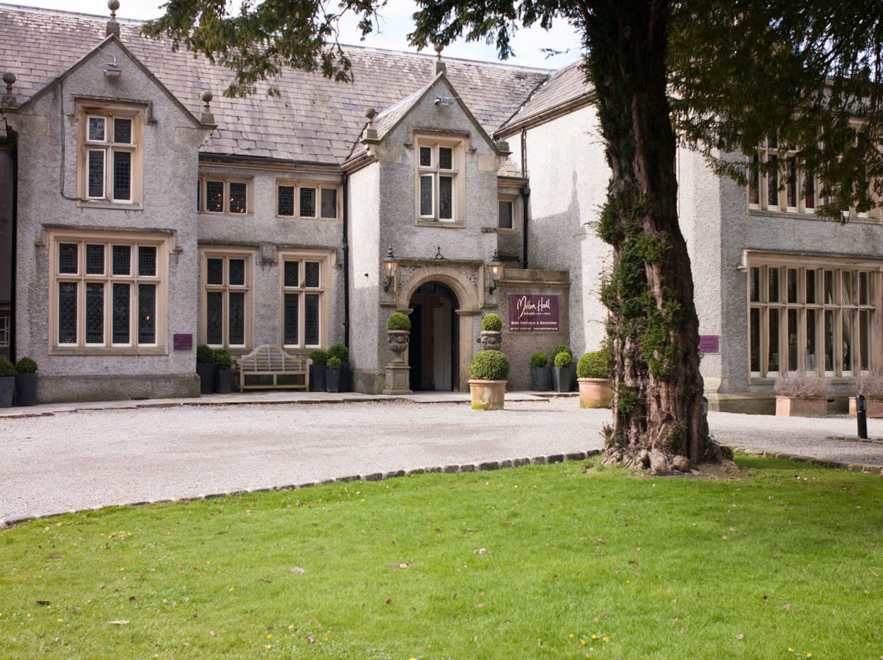 Mitton Hall photographed from the lawn, framed by the old tree in soft shade.