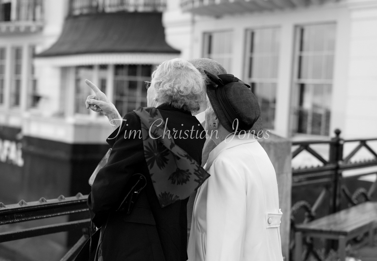 Black and white photo of three elderly guests looking out across the River Thames from the Trafalgar Tavern, Greenwich.