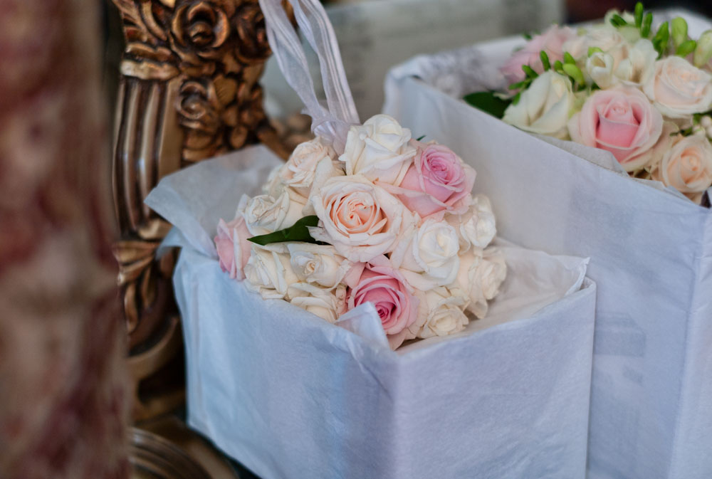 Rose bouquets in white boxes resting on an ornate chair in the bridal suite