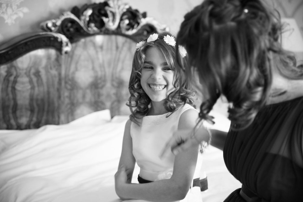 Young bridesmaid gives big smiles to her sister during morning preparations.