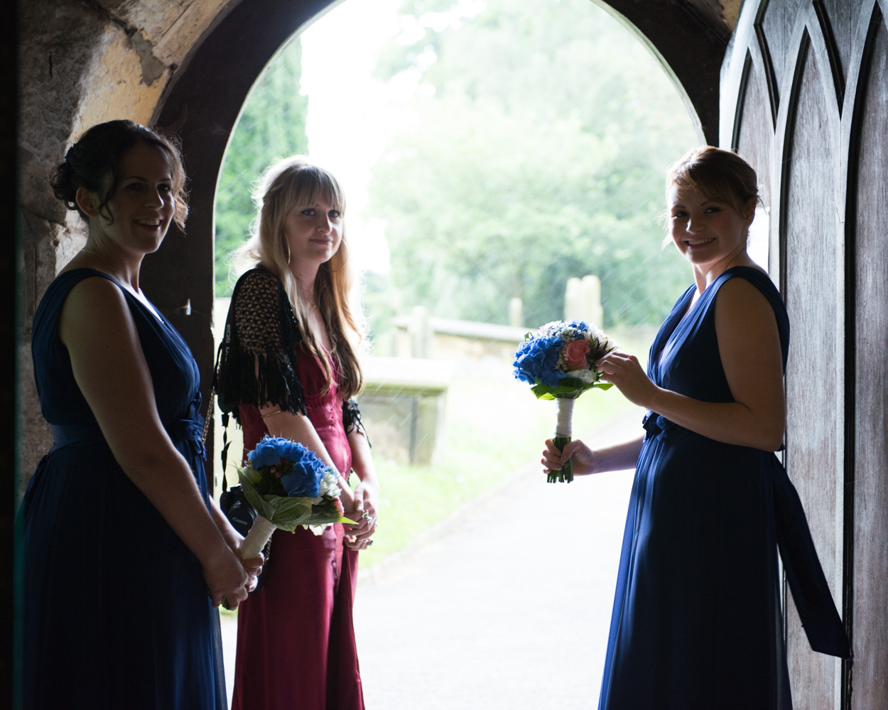 Bridesmaids shelter from the rain at Kirk Deighton Church, Wetherby