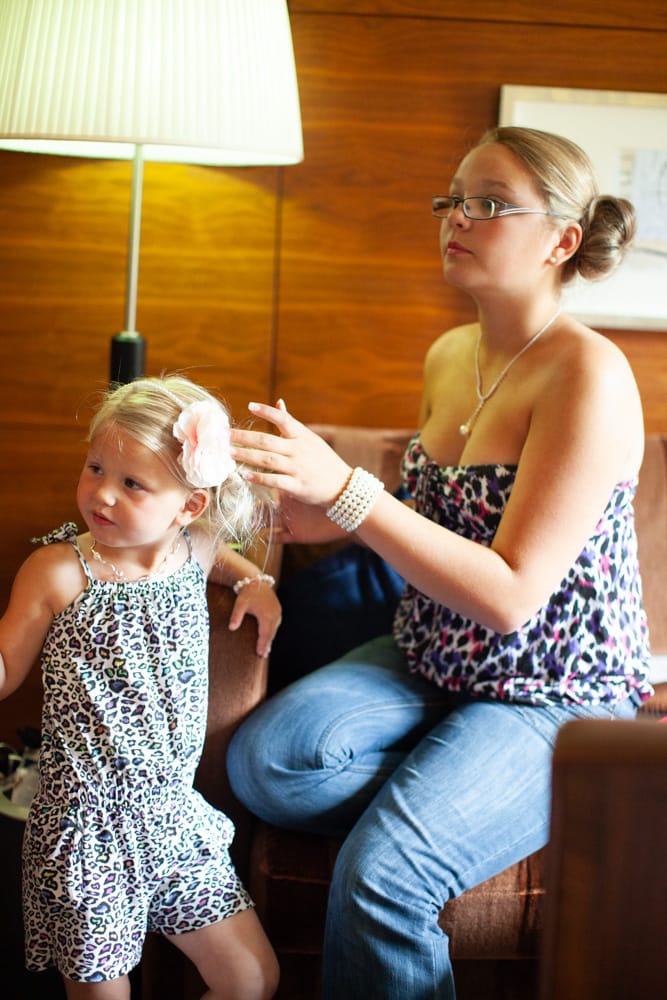 Two young bridesmaids sit in natural light during morning preparations.