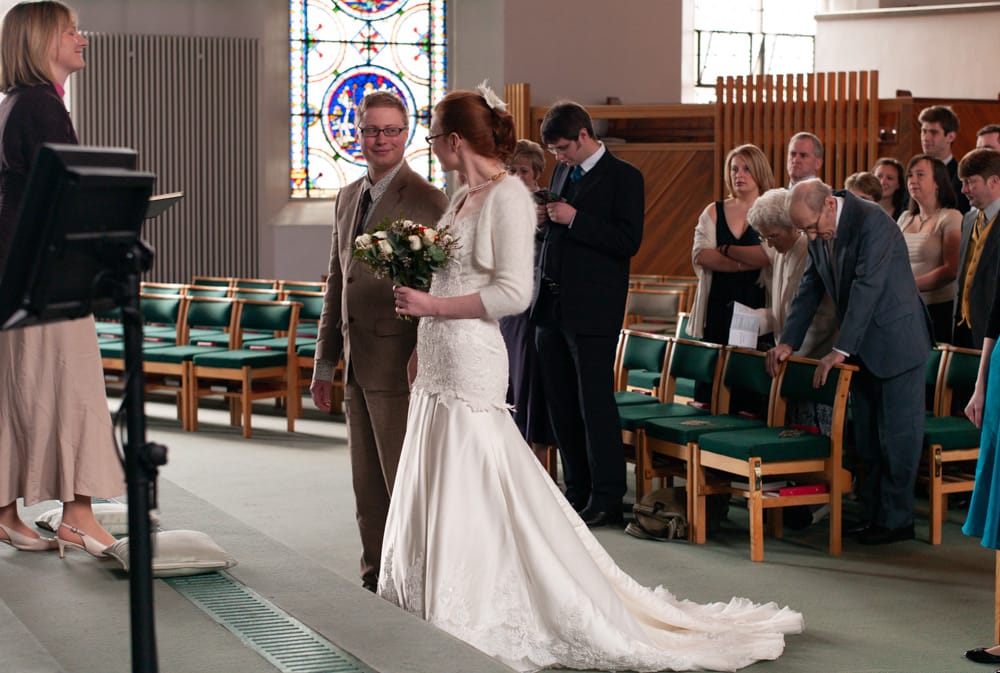 Bride meets groom at the altar in St George’s Church Leeds, minister smiling, guests seated.