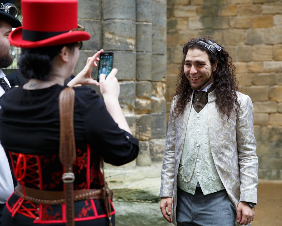 011 groom poses smiling for guest with red top hat kirkstall abbey wedding linsey and chris