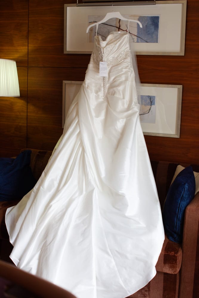 Gemma’s wedding dress draped across a sofa, hung neatly on a frame.