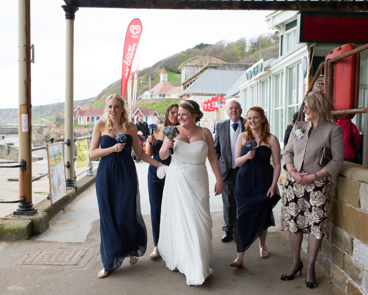 Candid wedding photography outside the Scarborough cliff lift, capturing relaxed, joyful moments before the ceremony.