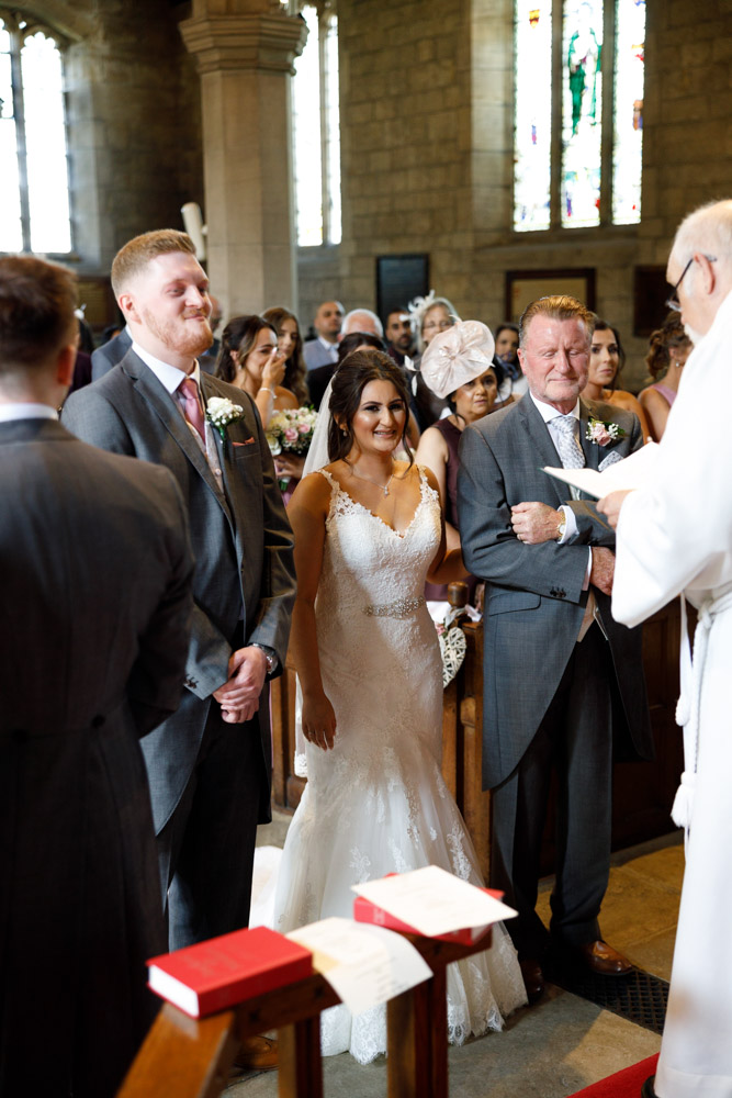 Groom beams with pride as the bride arrives, both listening intently to the minister’s welcome.