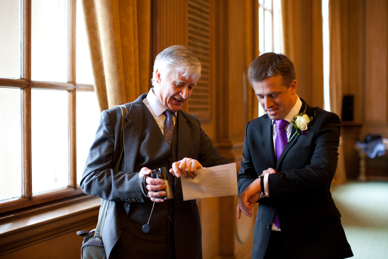 Groom jokingly checking his watch inside the Banquet Hall at Leeds Civic Hall.