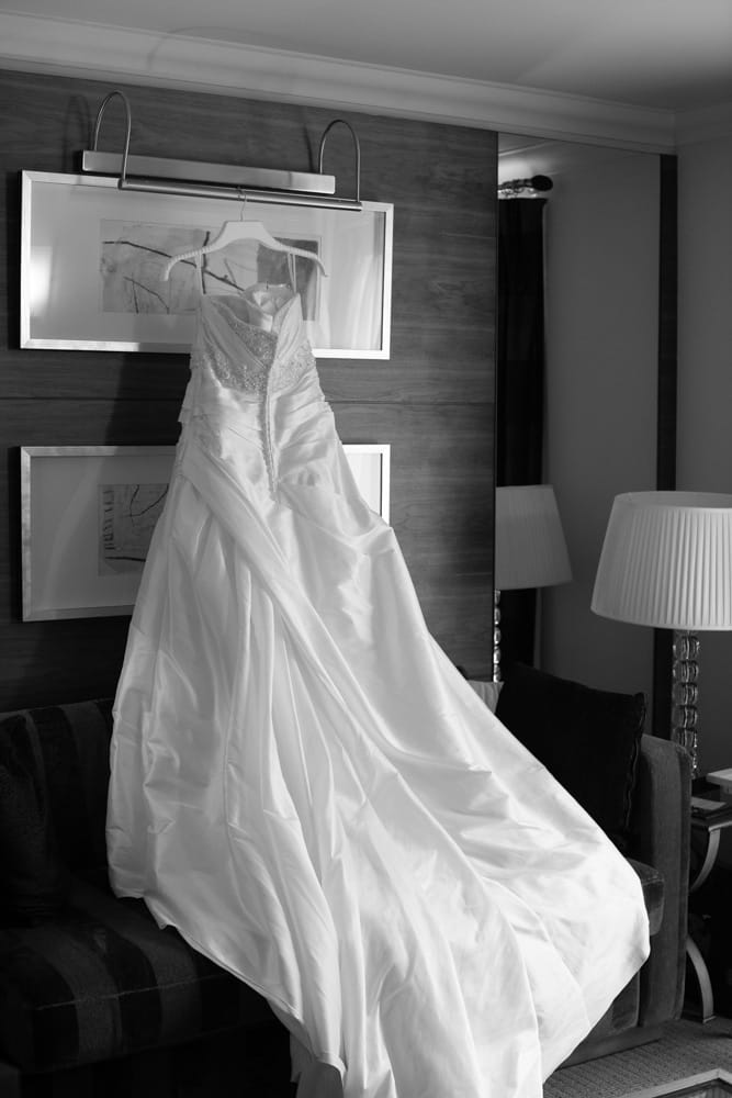 Black and white angle of Gemma’s wedding dress hanging across the sofa.