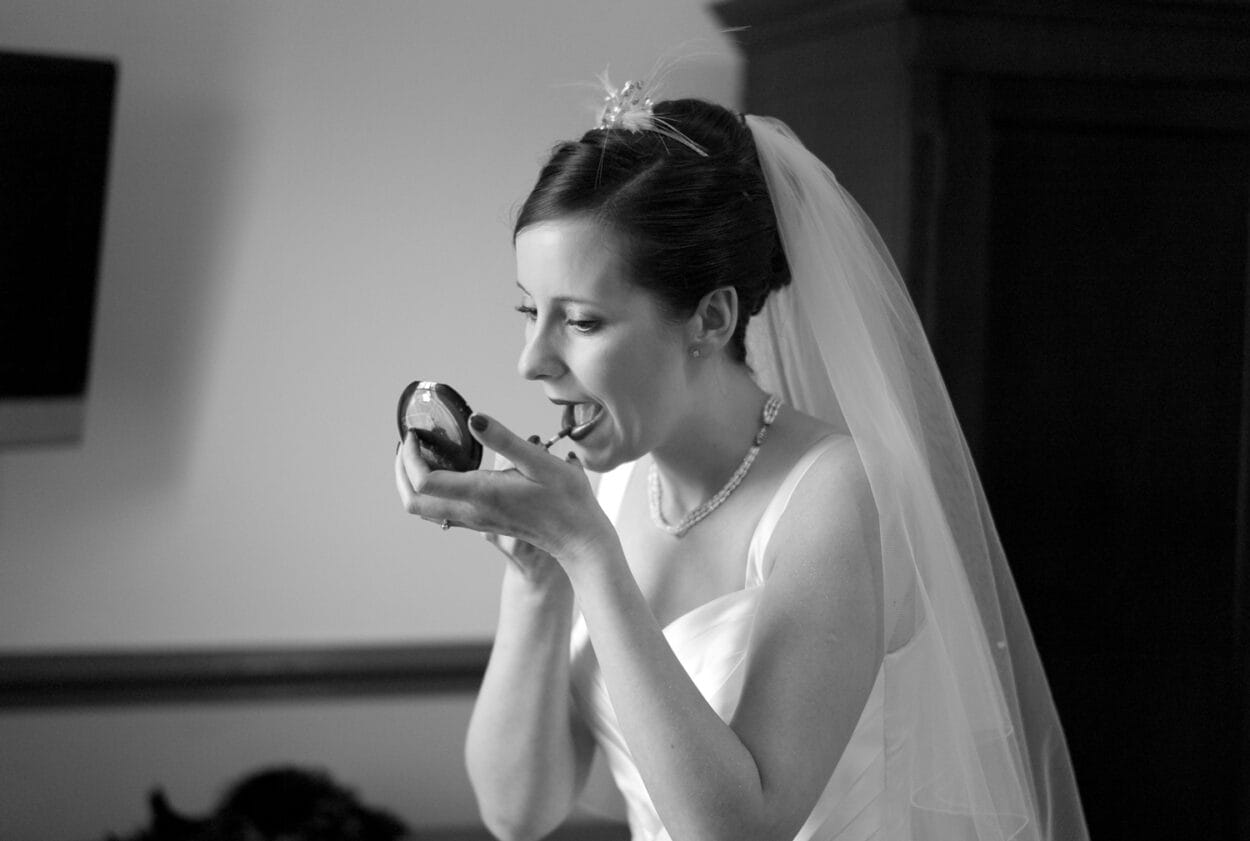 Black-and-white close-up capturing the emotion of the final makeup touches.