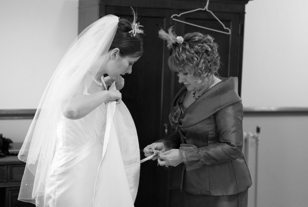 Mother of the bride helps tie the bustle on Emelie’s dress.