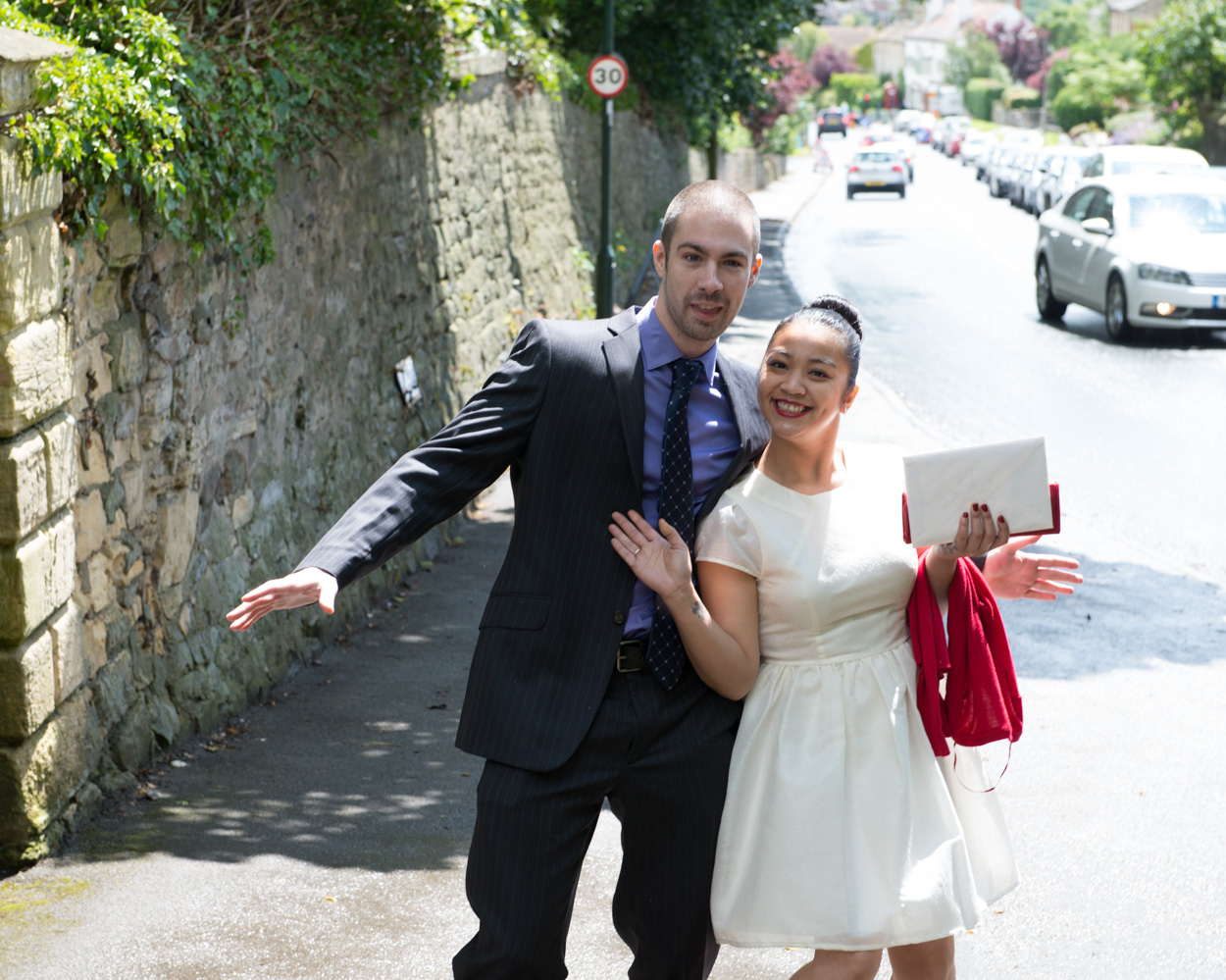 A couple arrive at the church posing together in bright sunshine